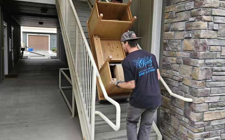 Movers carrying boxes through an apartment building corridor