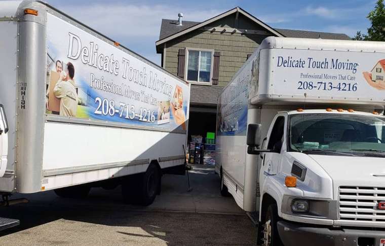 Delicate Touch movers carrying boxes out of a house in Boise